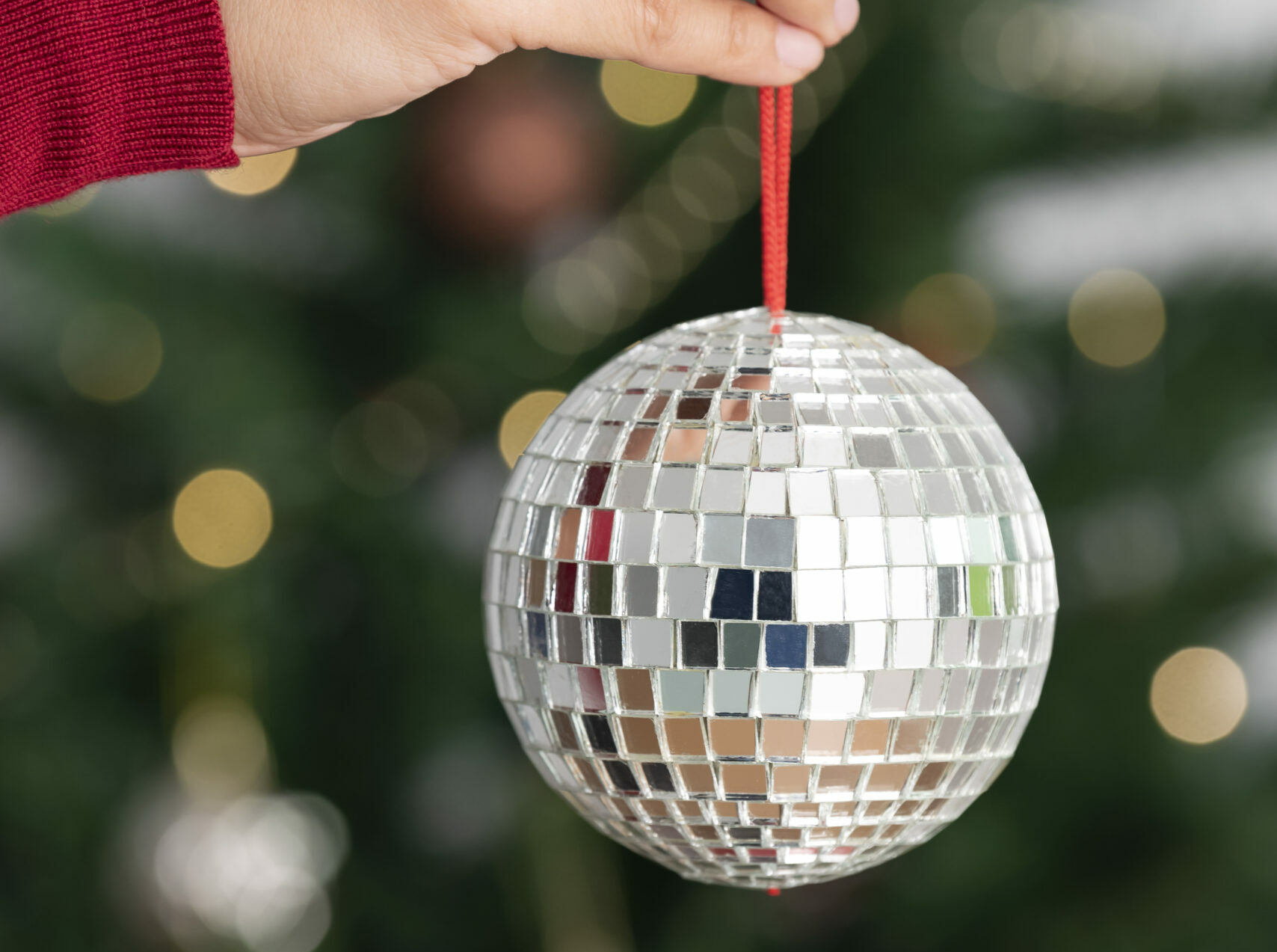 Christmas Music Night - Woman holding silver christmas disco ball on christmas tree back
