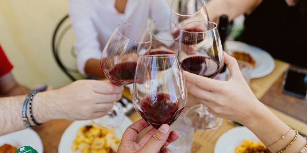 Brindisi tra amici in trattoria a Cattolica, tra piatti tipici della tradizione romagnola e calici di vino rosso. Il gusto autentico della convivialità.